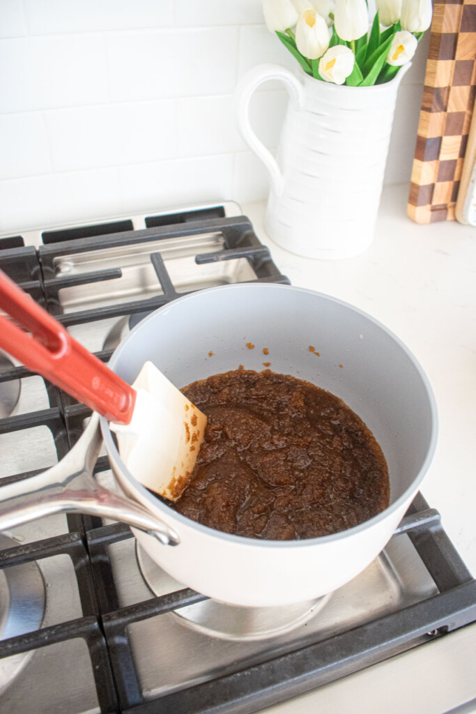 brown sugar and brown butter being stirred in a small pot on the stovetop.