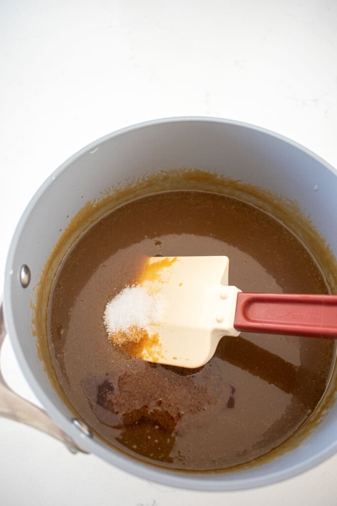 salt and vanilla being added to brown butter butterscotch sauce.