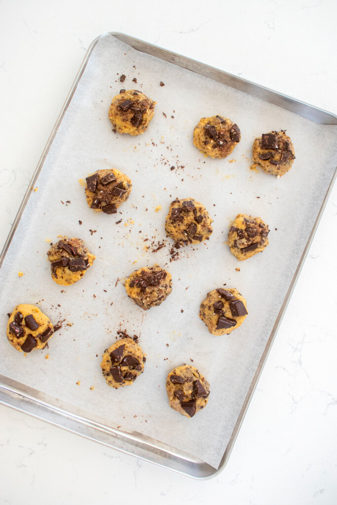 baking sheet of candy cane crunch dark chocolate cookie dough balls on a marble counte.r