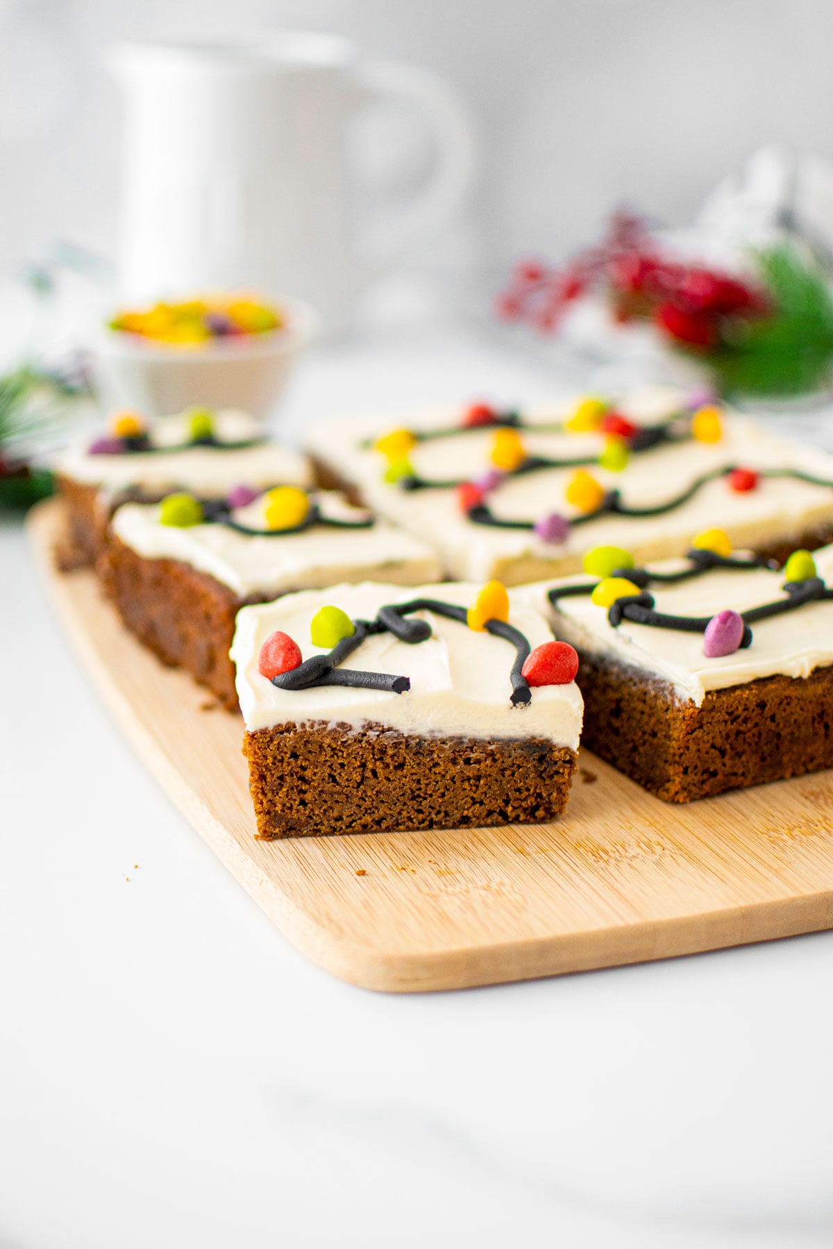 christmas lights gingerbread snack cake cut into square slices on a wood cutting board on a marble counter.