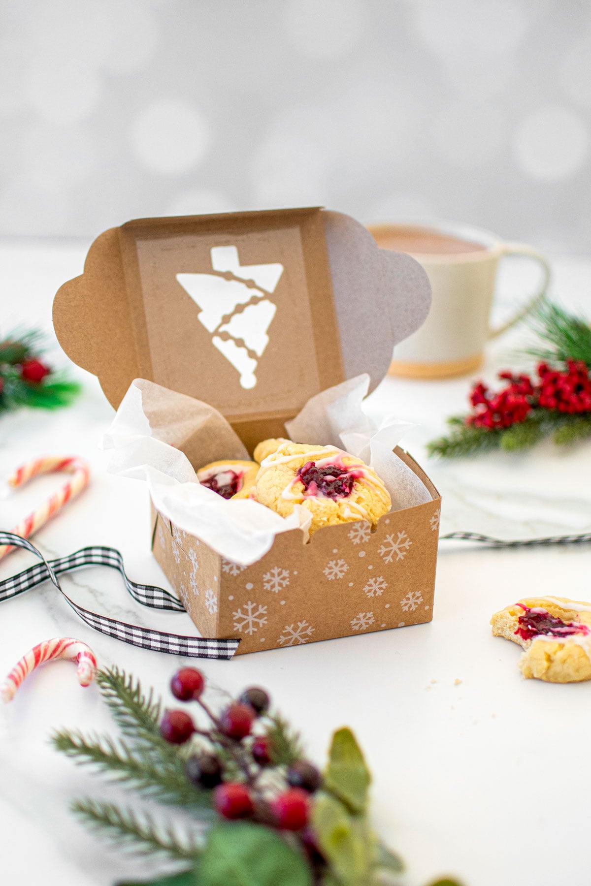 christmas cookie box with jam thumbprint cookies inside on a white marble counter.