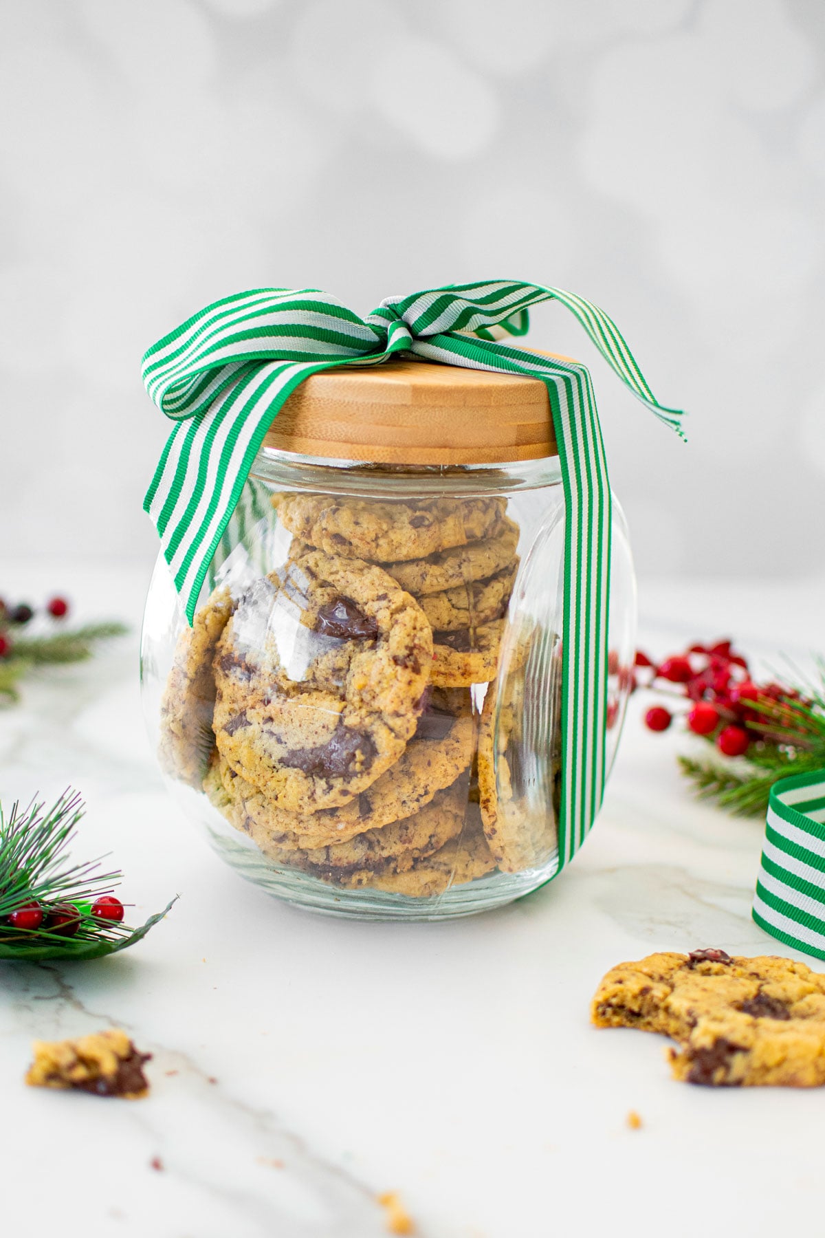 glass cookie jar with a green and white stripe ribbon tied around it on a white marble counter.