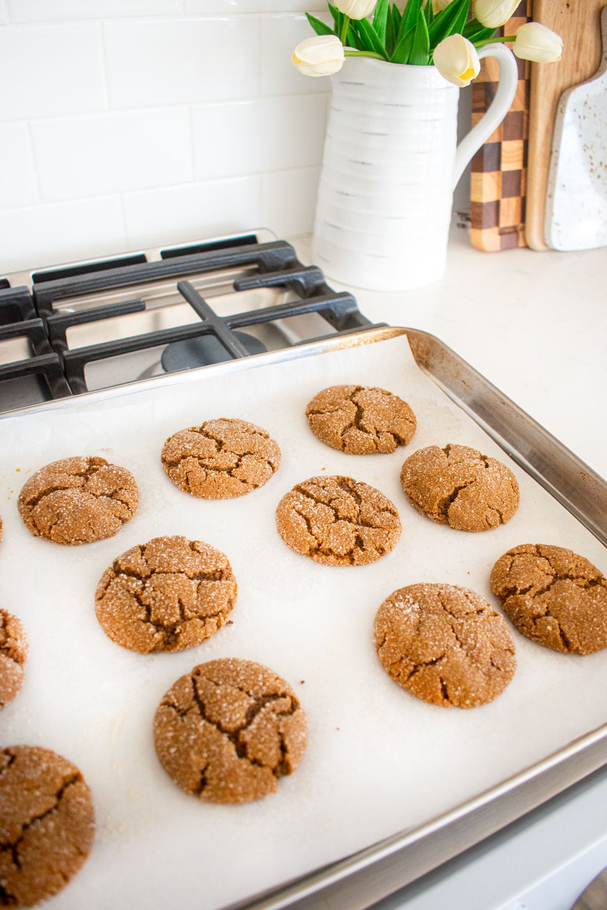 eggless sourdough molasses cookies cooling on a baking sheet on top of the oven.