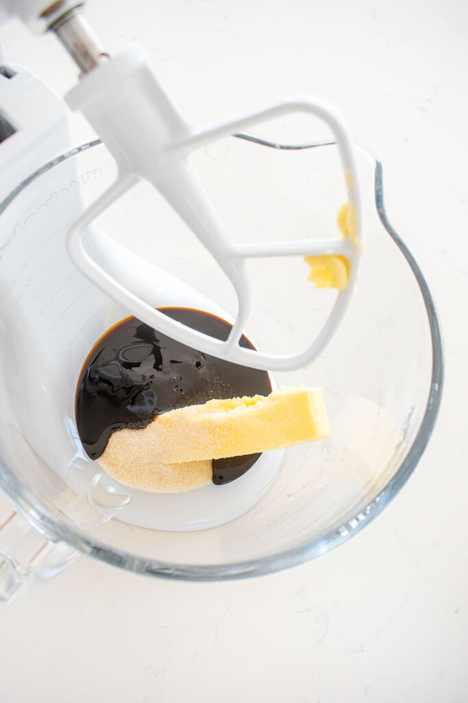 butter sugar and molasses in a glass mixing bowl on a marble counter.