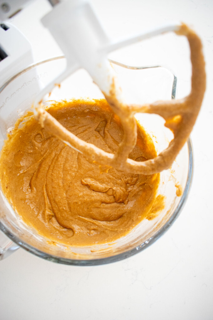 gingerbread banana bread batter in a glass mixing bowl on a white marble counter.