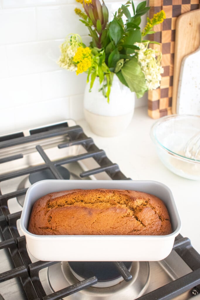 gingerbread banana bread cooling in a loaf pan on top of the stove.