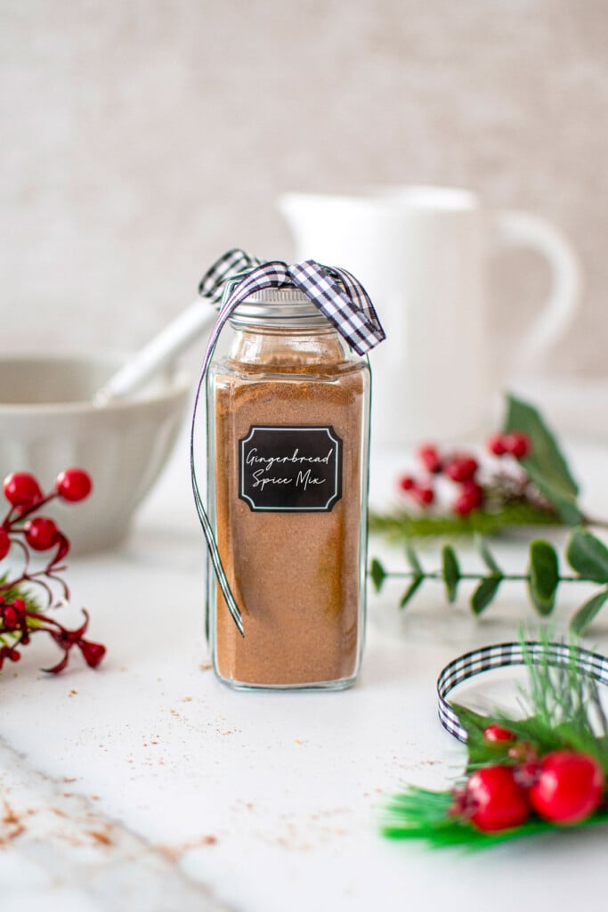 homemade gingerbread spice mix in a spice jar on a marble counter.