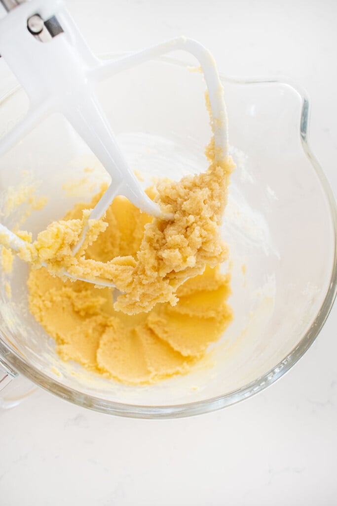 creamed butter and sugar in a mixing bowl on a white marble counter.