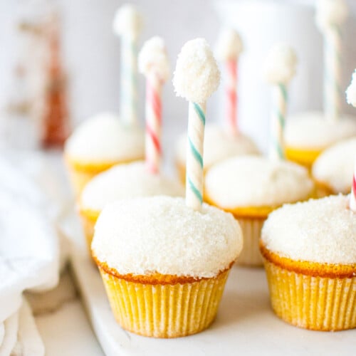 north pole cupcakes on a marble serving board on a table with holiday decor.