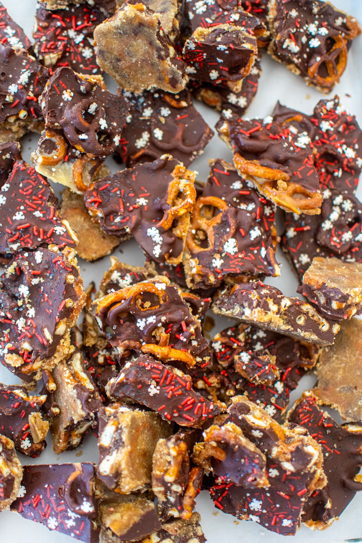 peanut butter pretzel christmas crack pieces on a baking sheet on a marble counter.