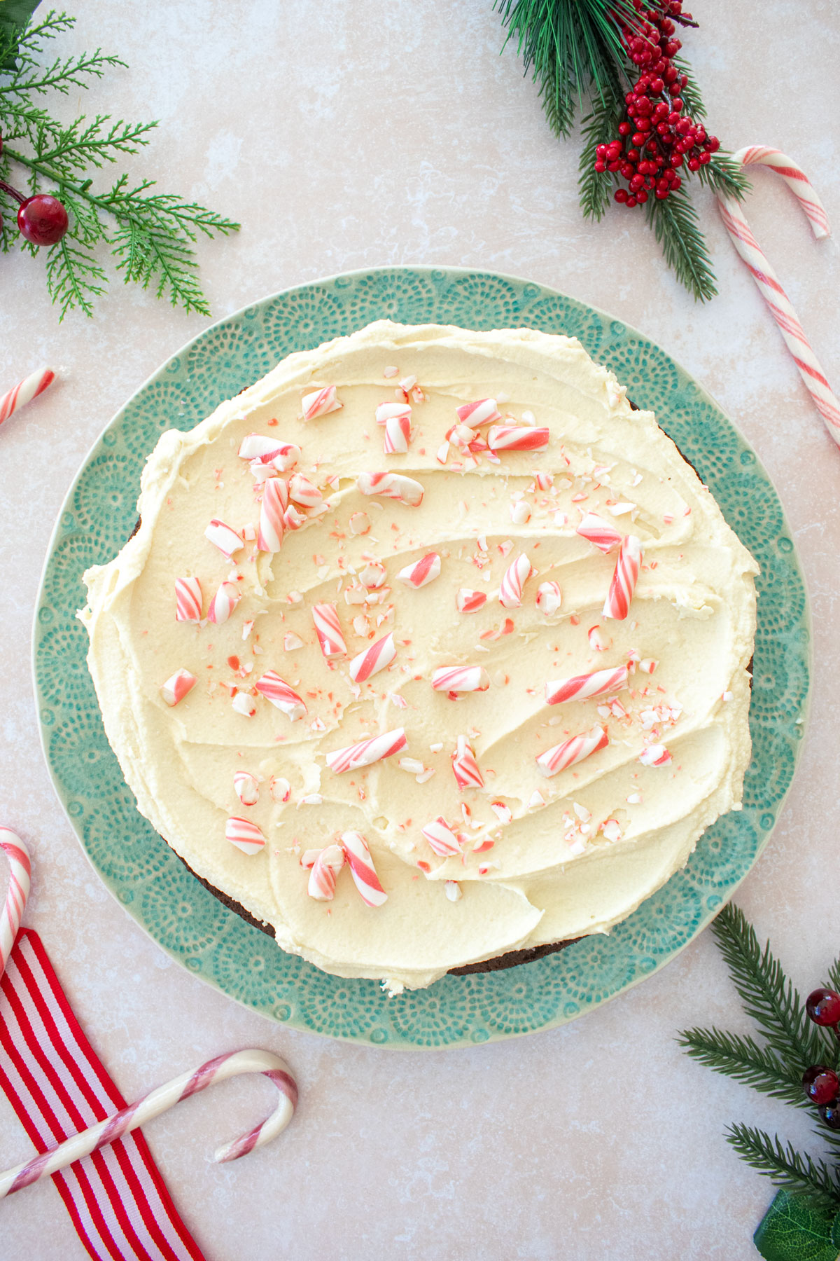 peppermint bark snack cake with candy canes on top on a green cake plate on a table.