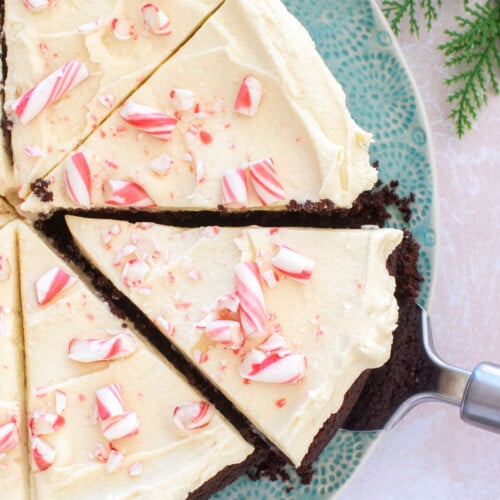 peppermint bark snack cake cut into slices on a green cake plate.