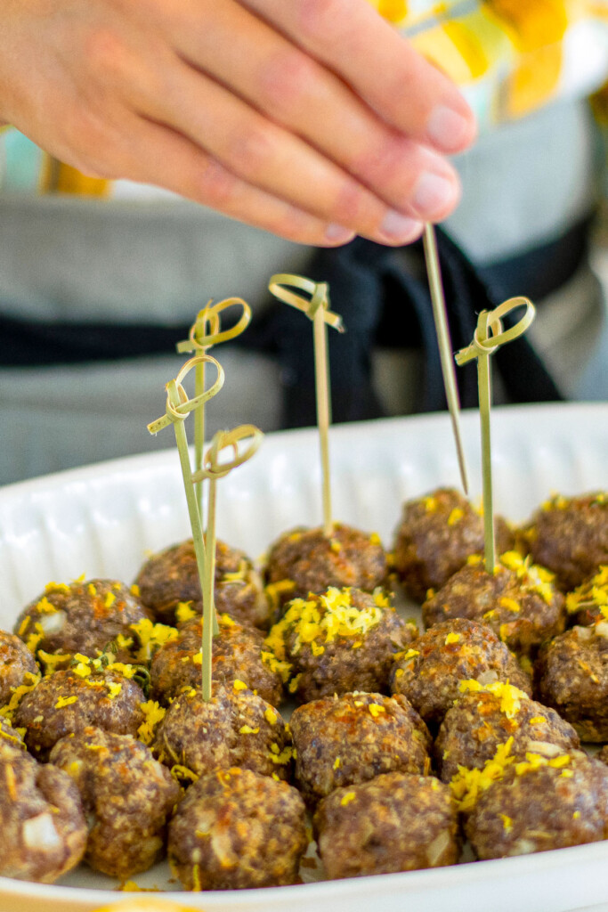 woman placing toothpicks in rosemary meatball bites.