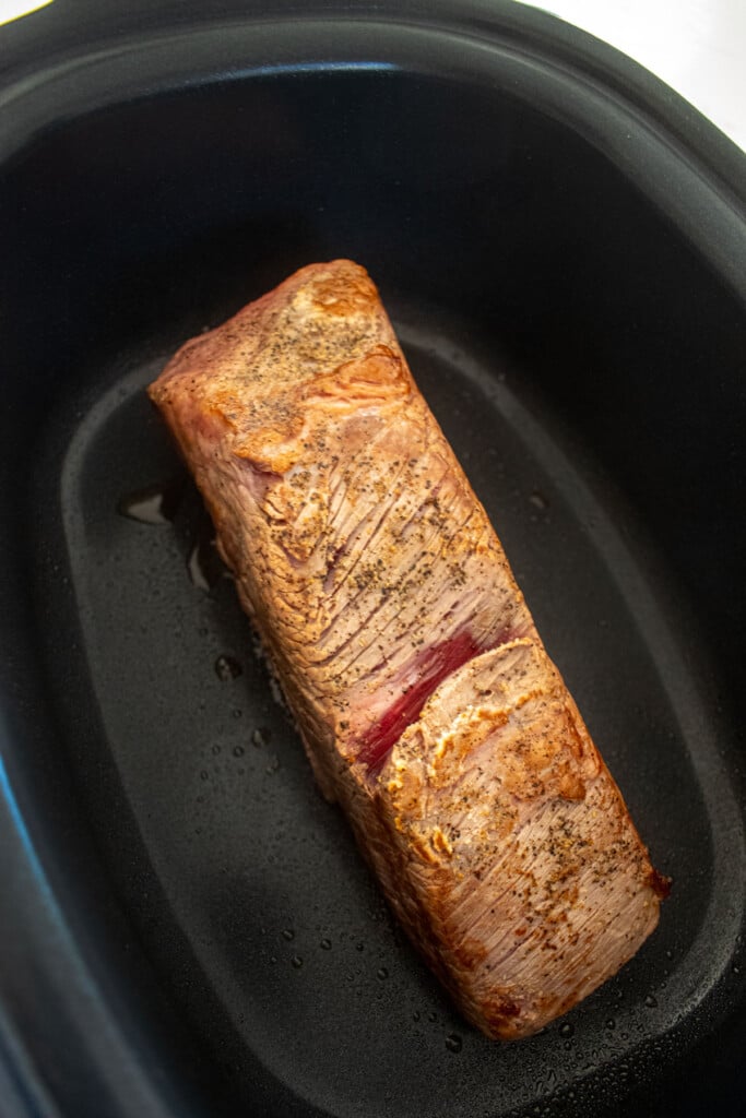 brisket being seared in a slow cooker.