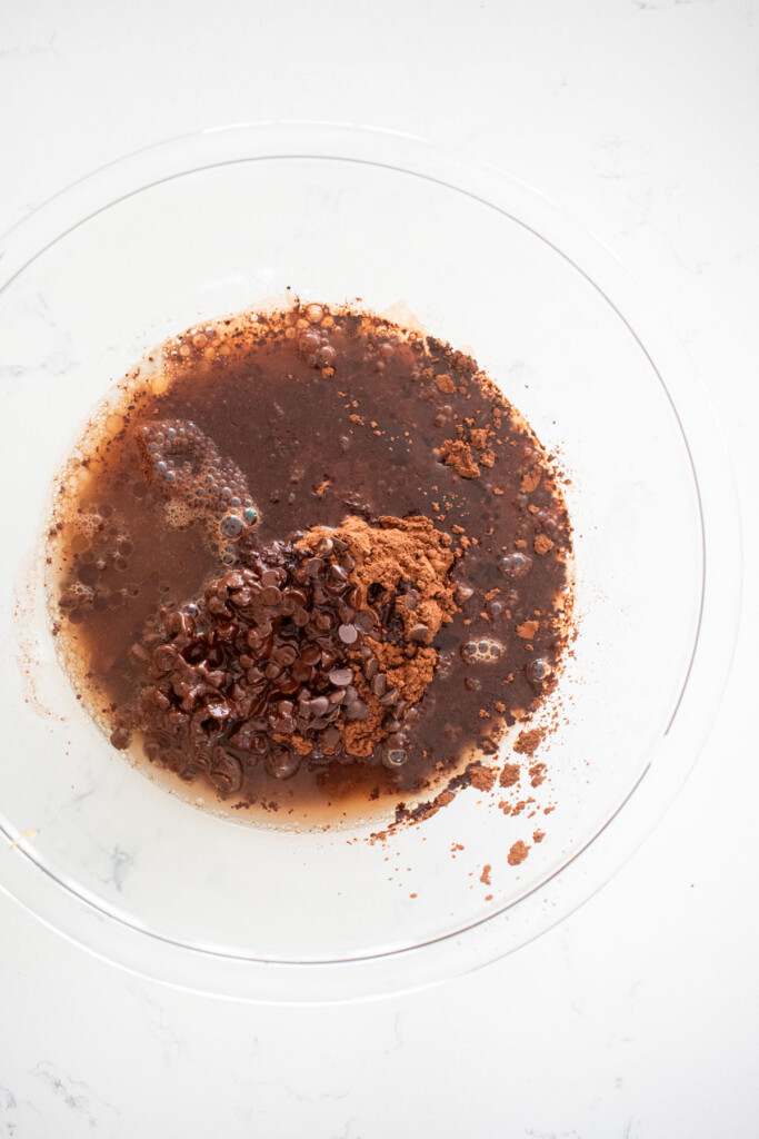 wet ingredients for vegan brownies in a glass mixing bowl on a white marble counter.