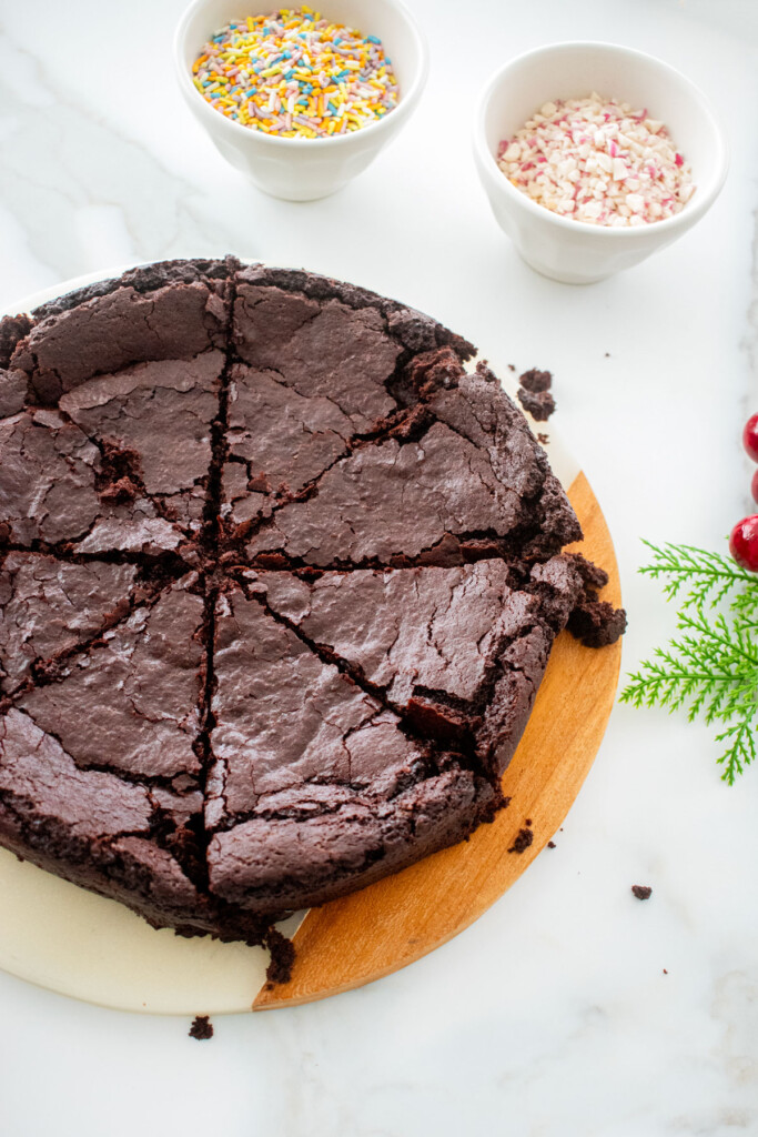 round brownies on serving board cut into 8 triangle slices on a white marble counter.