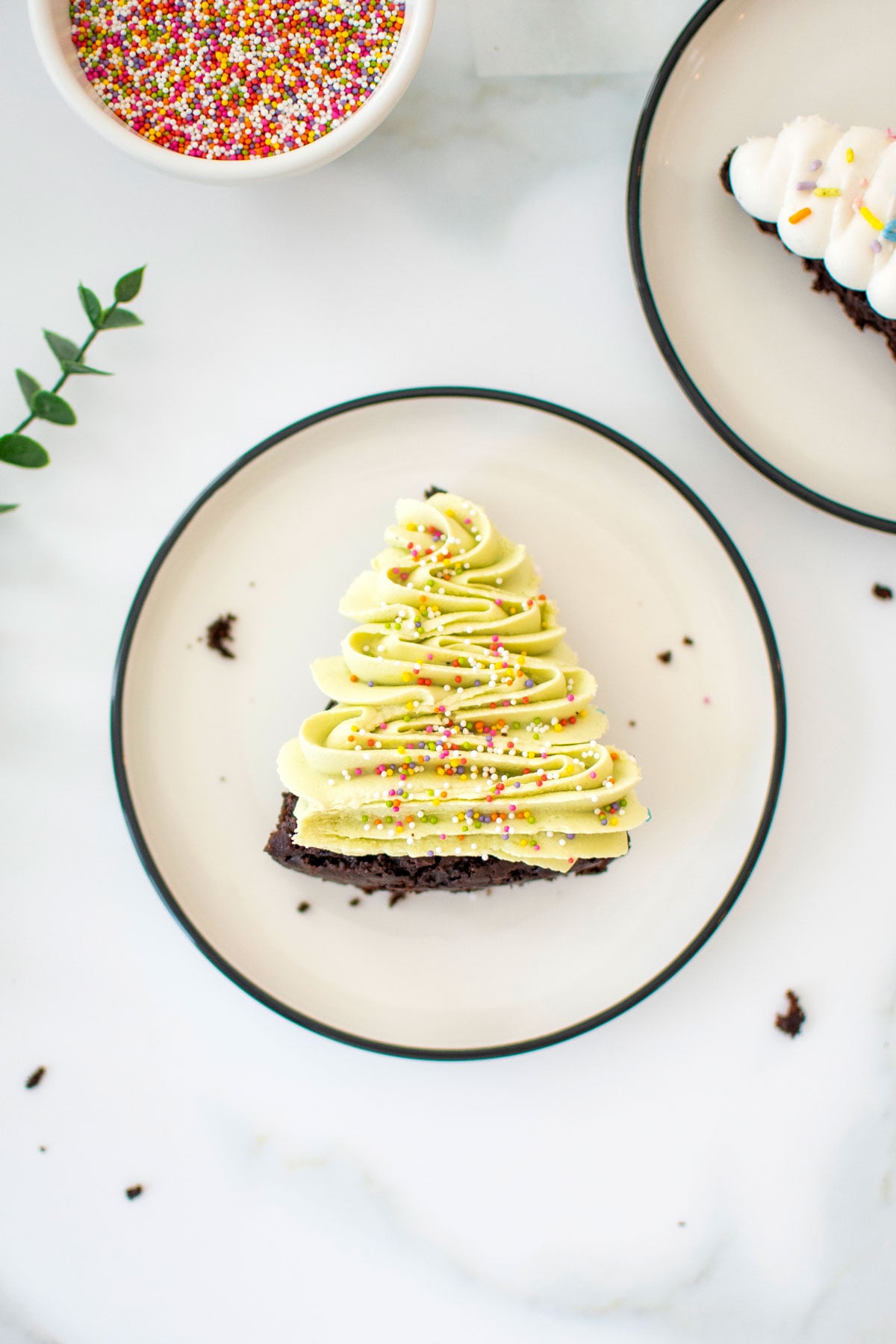 vegan christmas tree brownie with sprinkles on a plate on a marble counter.