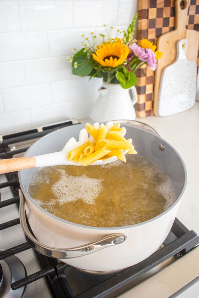 penne pasta being cooked in a stock pot on the stovetop.
