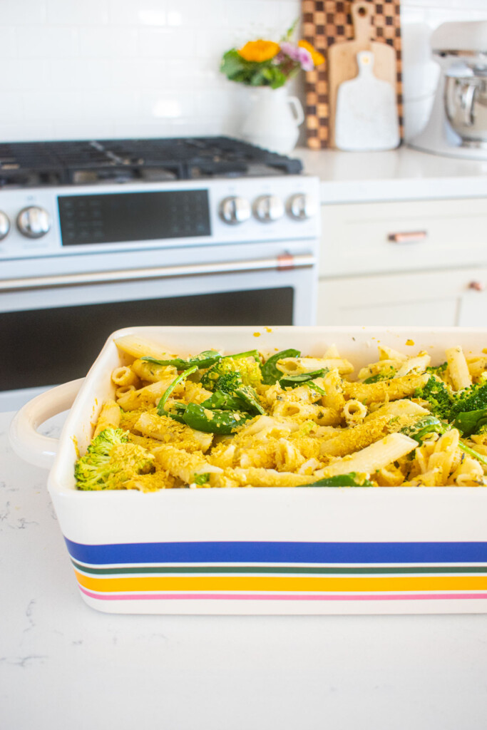 butter lemon pasta mixed together in a striped baking dish on the kitchen counter.