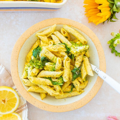 bowl of baked butter lemon pasta without cheese in a pasta bowl on a table with fresh flowers and lemons.