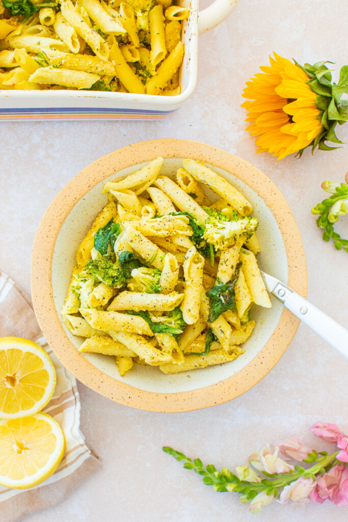 bowl of baked butter lemon pasta without cheese in a pasta bowl on a table with fresh flowers and lemons.