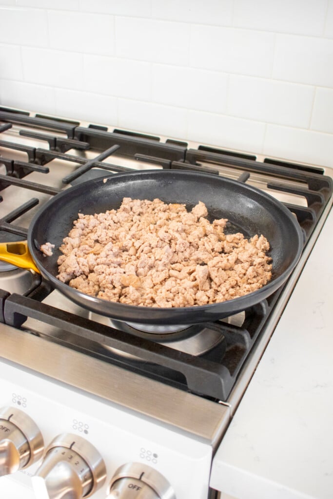 ground chicken in a large skillet cooking on the stove. 