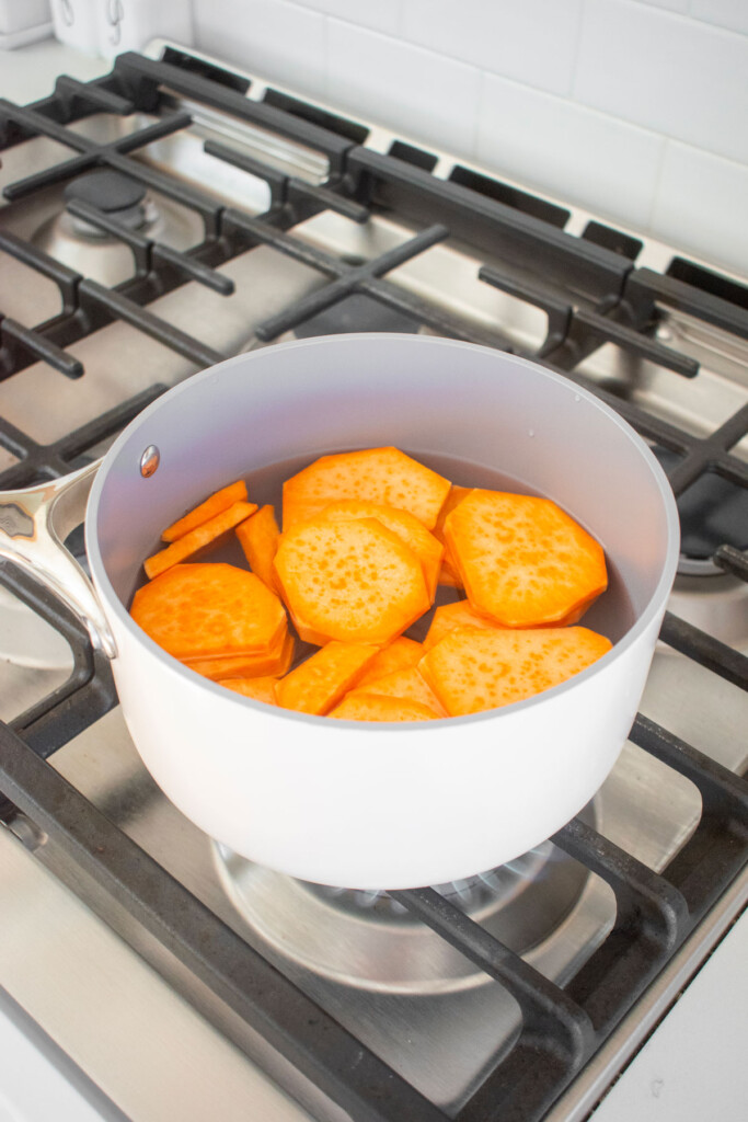 sweet potatoes slices boiling in a pot over the stove.