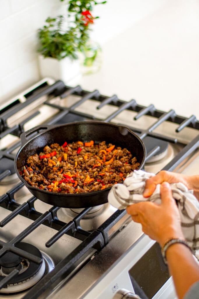 cooked ground pork, peppers and onions in a cast iron skillet on the stove.