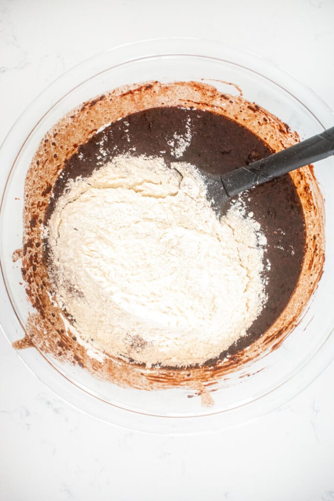 ingredients for eggless chocolate ganache brownies in a glass mixing bowl on a white marble counter.