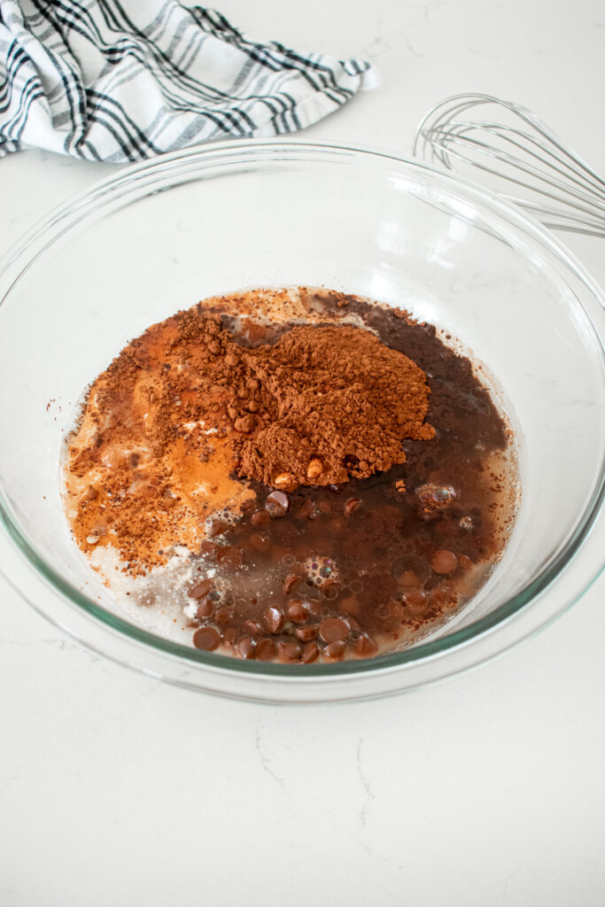 wet ingredients for eggless brownies in a large mixing bowl on a white marble counter.