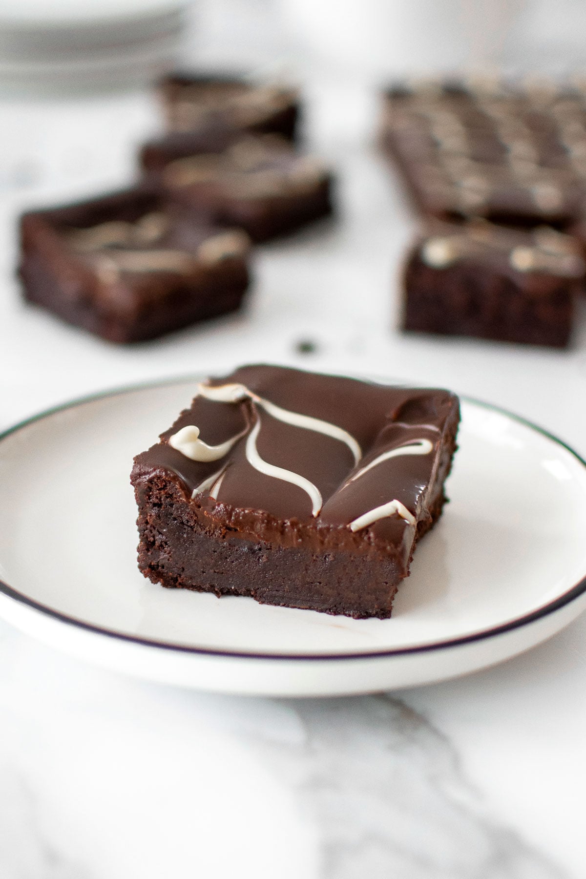 eggless chocolate ganache brownie on a plate on a white marble counter.