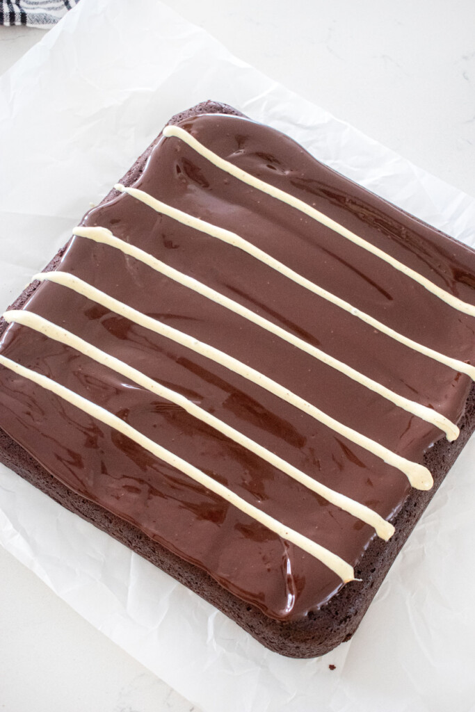 eggless chocolate ganache brownies with melted white chocolate lines drawn on top.