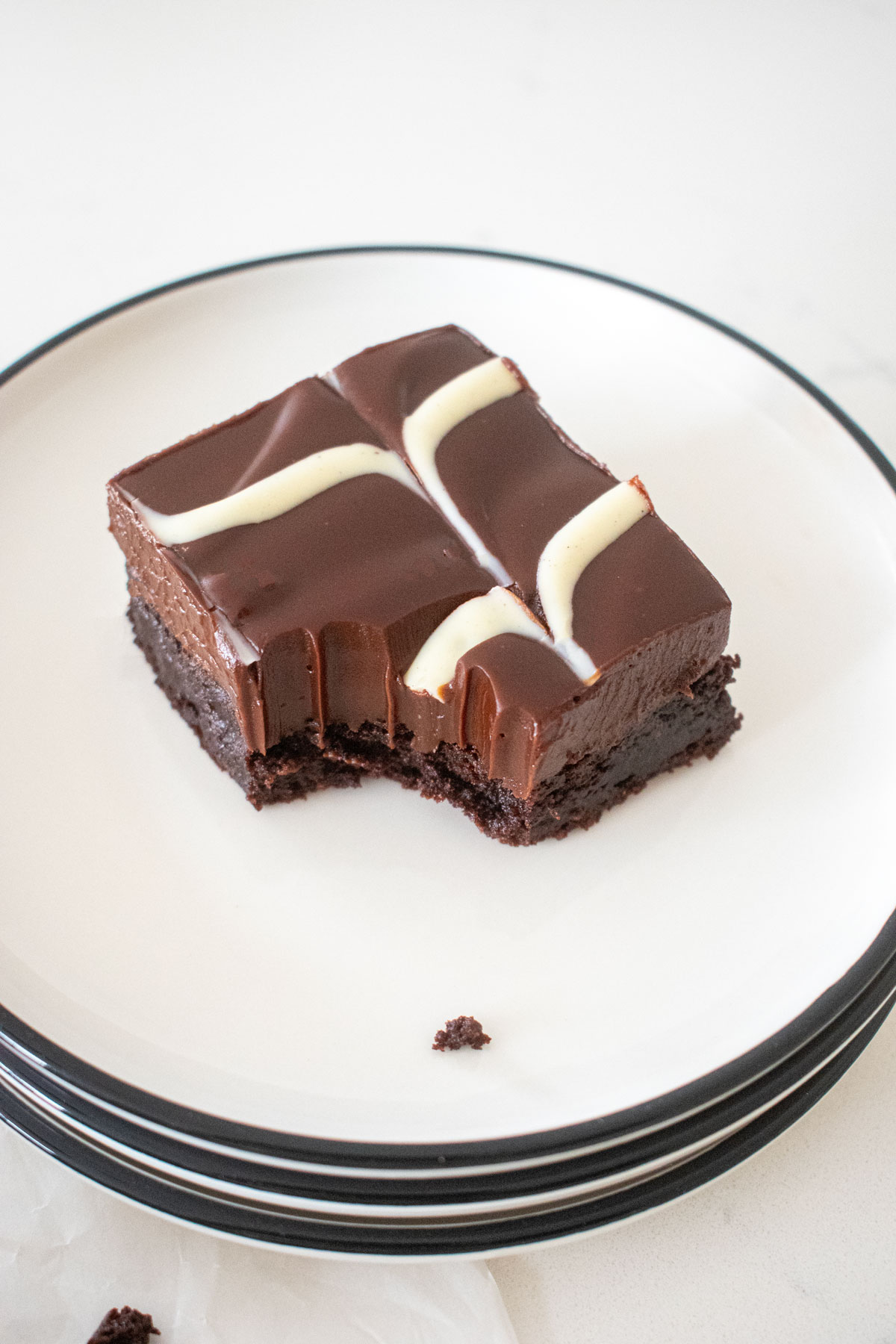 eggless chocolate ganache brownie with a white chocolate chevron design with a bite taken out on a plate.