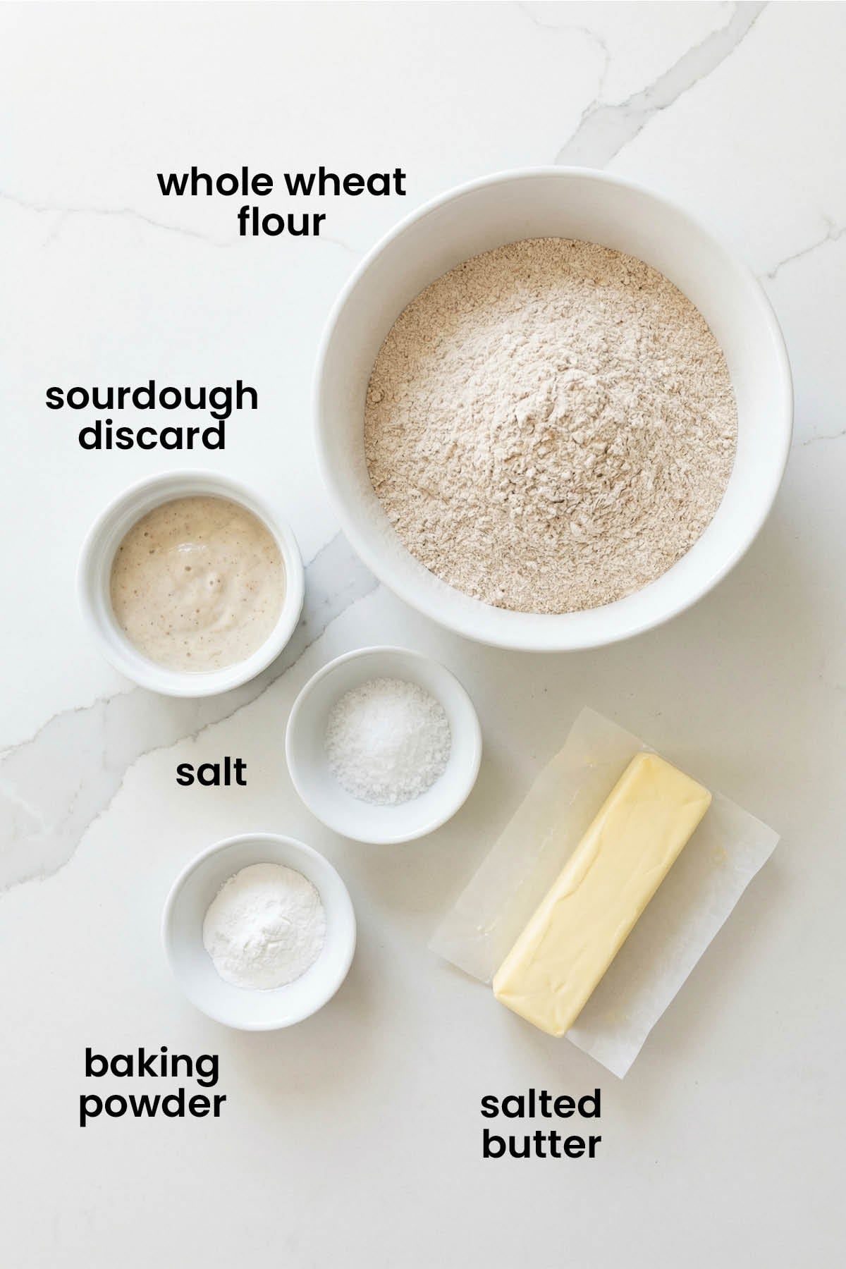 individual ingredients for homemade sourdough discard whole wheat crackers laid out against a white background.