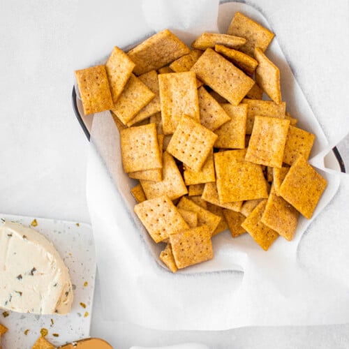 homemade sourdough discard whole wheat crackers in a serving dish on a table with cheese.