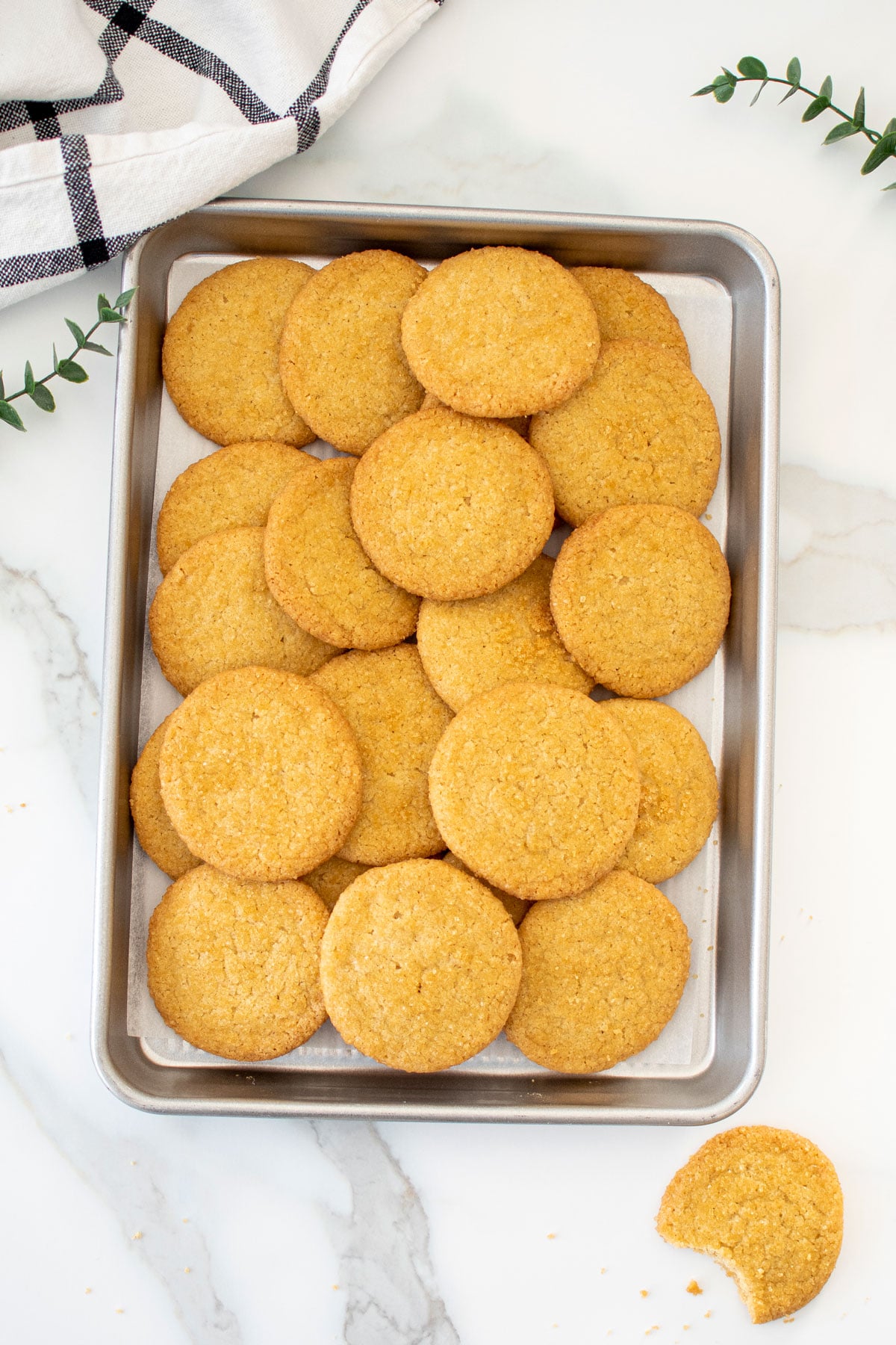 baking sheet of olive oil shortbread cookies on a white marble counter.