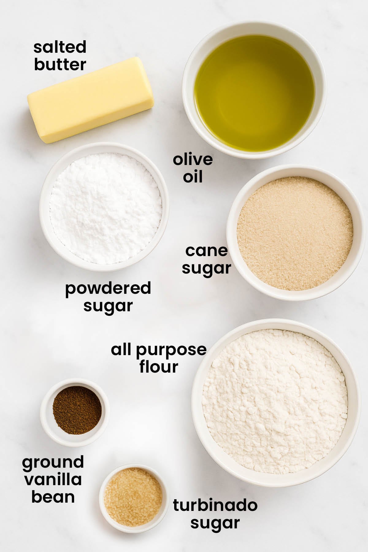 individual ingredients for olive oil shortbread cookies on a white marble kitchen countertop.