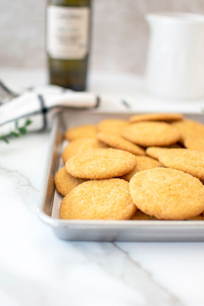 baking sheet of olive oil shortbread cookies on a white marble counter.