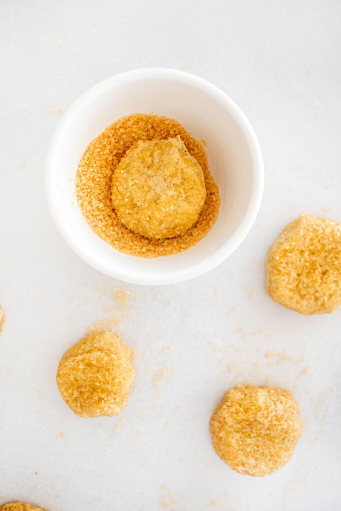 olive oil shortbread cookie dough in a bowl of turbinado sugar.