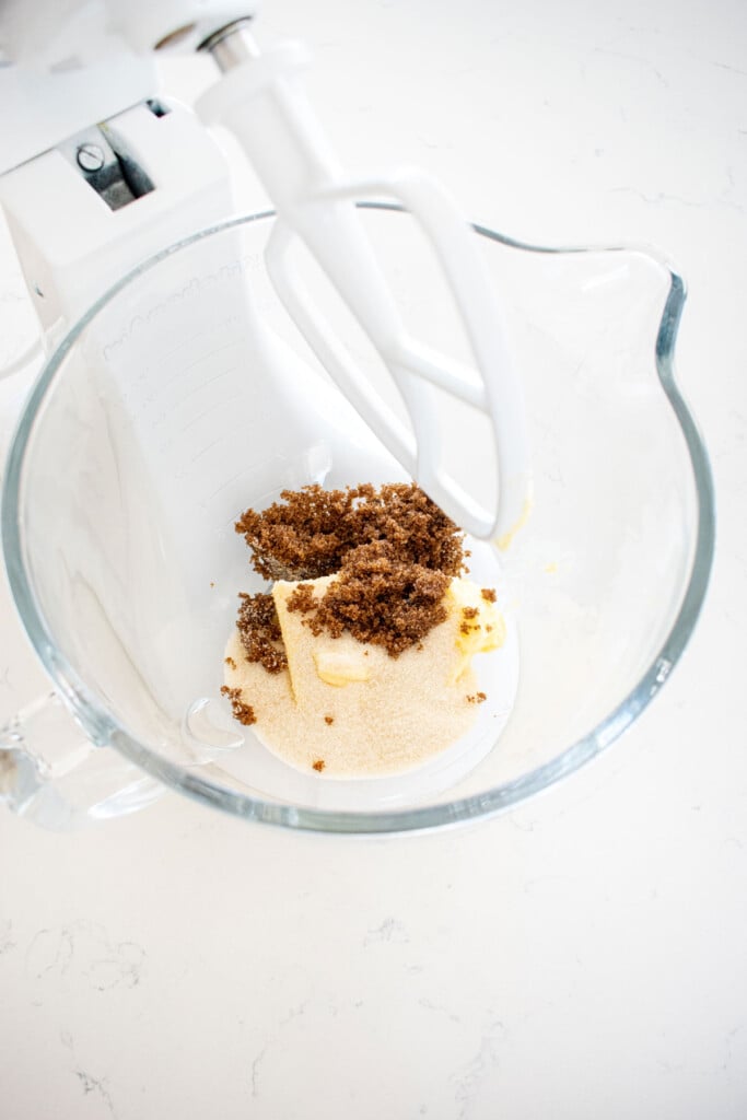 butter sugar and vanilla in a glass mixing bowl on a marble counter.