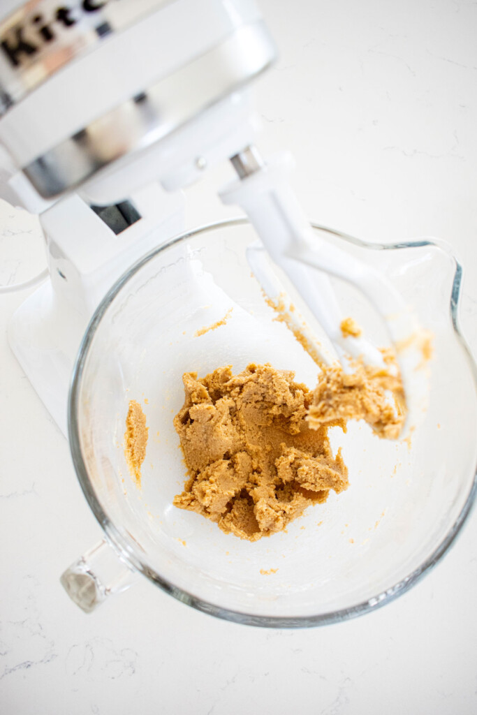 creamed butter and sugar in a glass mixing bowl on a marble counter.