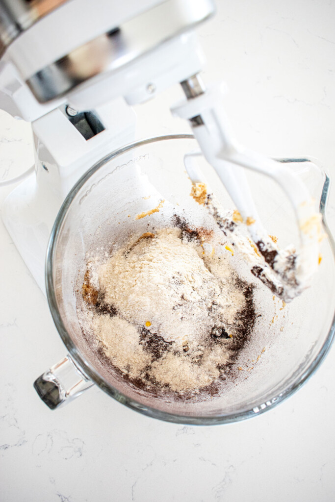 ingredients for sea salt black cocoa biscotti in a glass mixing bowl on a marble counter.