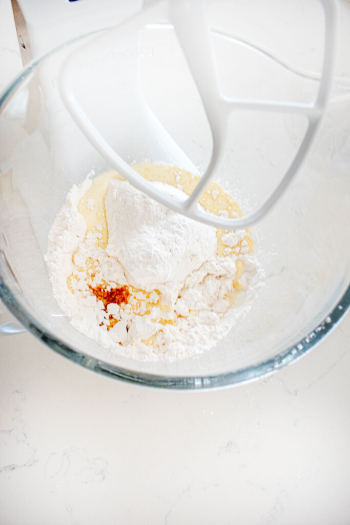 ingredients for vanilla icing in a glass mixing bowl on a marble counter.