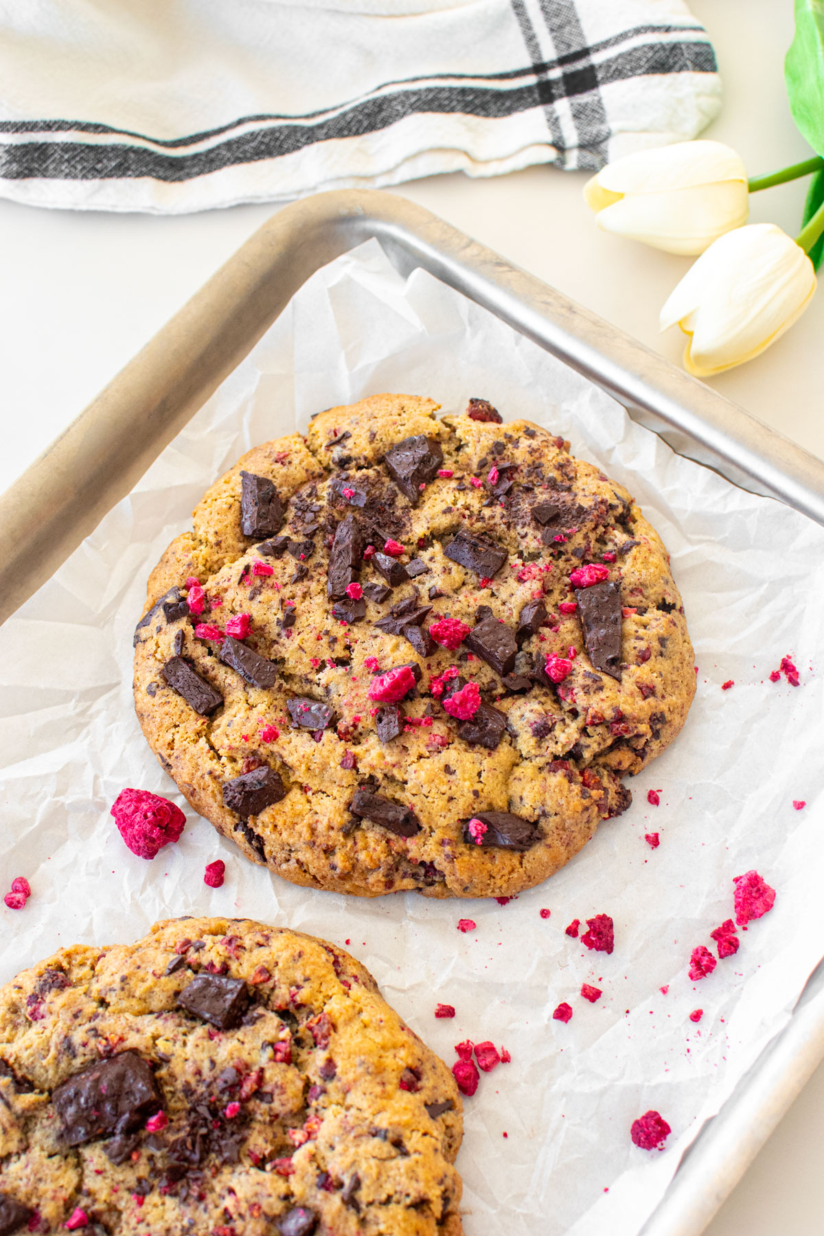 vegan raspberry chocolate chip cookies on a baking sheet on a white marble counter.
