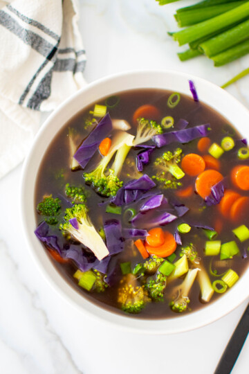 5 ingredient bone broth vegetable soup in a white bowl on a marble countertop.
