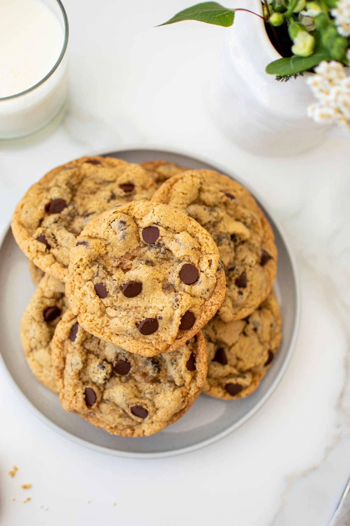 eggless chocolate chip cookies on a plate with a glass of milk.