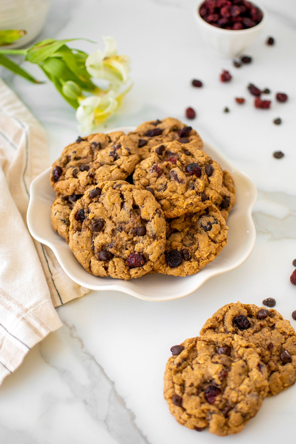 eggless oatmeal cranberry chocolate chip cookies on a plate on a white marble countertop.