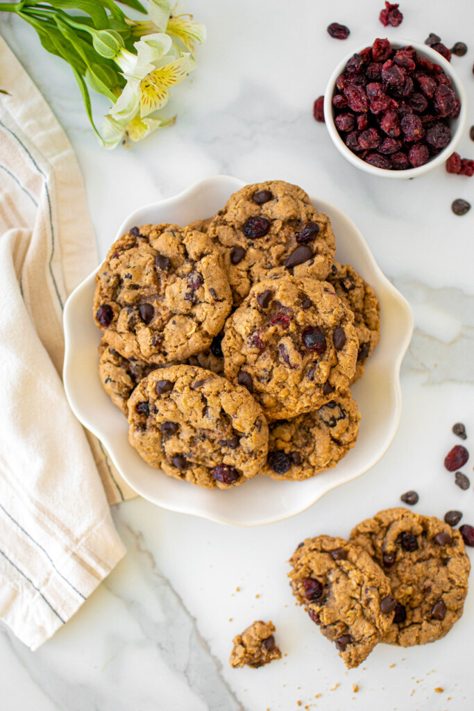 eggless oatmeal cranberry chocolate chip cookies on a plate on a white marble countertop.