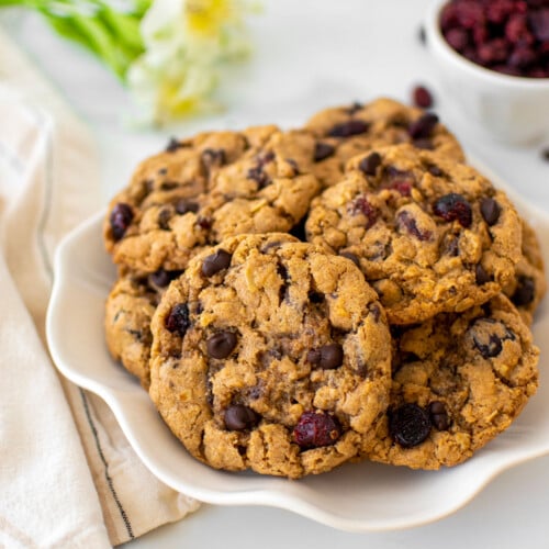 eggless oatmeal cranberry chocolate chip cookies on a plate on a white marble countertop.