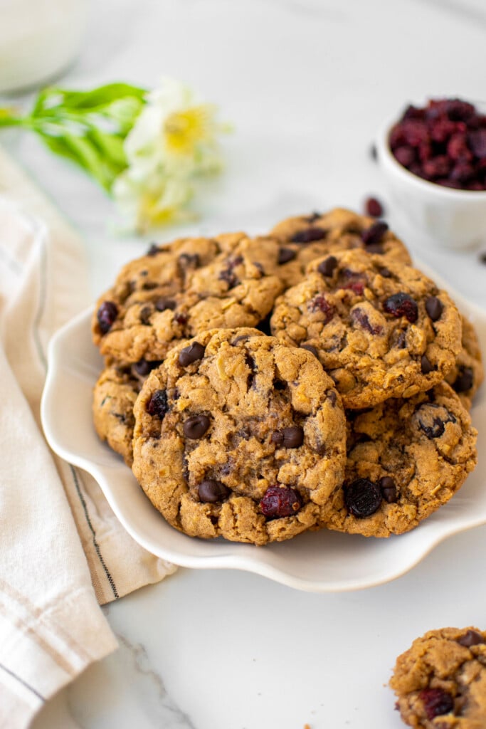 eggless oatmeal cranberry chocolate chip cookies on a plate on a white marble countertop.